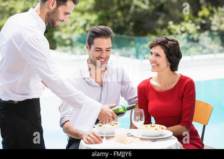 Smiling waiter serving couple de vin rouge Banque D'Images