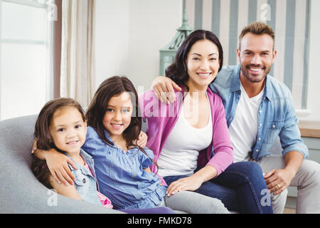 Heureux parents assis avec des enfants sur canapé Banque D'Images