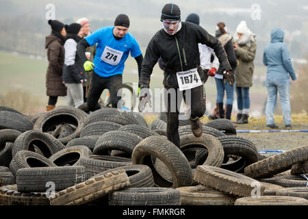 Bischofsheim, Allemagne. Mar 12, 2016. Les participants de la course extrême bataille Braveheart escalade un obstacle à Bischofsheim, Allemagne, 12 mars 2016. Près de 2 700 coureurs ont à gérer un 30 km avec 45 obstacles. Le extremerun mène à travers de l'eau très froide, la boue des fosses et feu chaud d'obstacles. Il est dit être l'un des plus difficiles en Europe. PHOTO : DANIEL KARMANN/dpa/Alamy Live News Banque D'Images