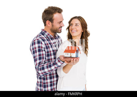 Happy young couple holding model house Banque D'Images