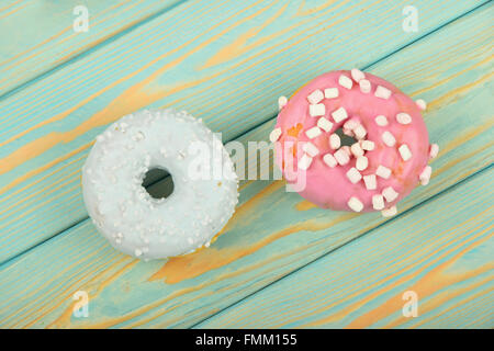 Bague ronde deux beignets, l'une en bleu avec blanc glaçage décoration garniture sprinkles et rose avec de petites guimauves à peint blu Banque D'Images