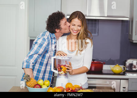 Man kissing woman la préparation de jus de fruits Banque D'Images