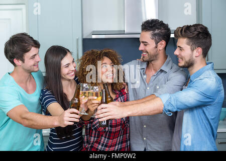 Multi-ethnic friends toasting beer and wine in kitchen Banque D'Images