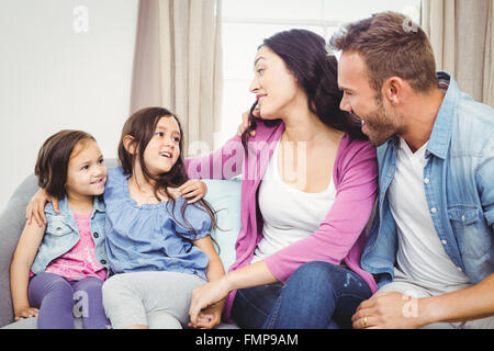 Heureux parents assis avec ses filles sur canapé Banque D'Images