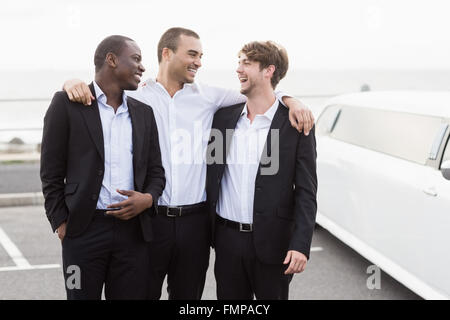 Beaux hommes posant à côté d'une limousine Banque D'Images