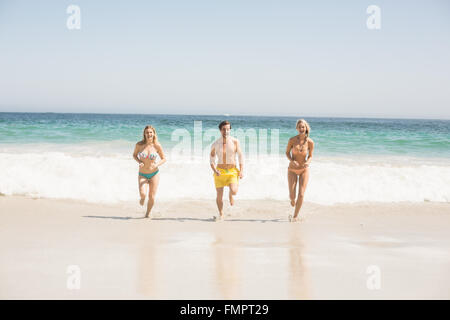 Heureux les jeunes amis s'exécutant sur la plage Banque D'Images