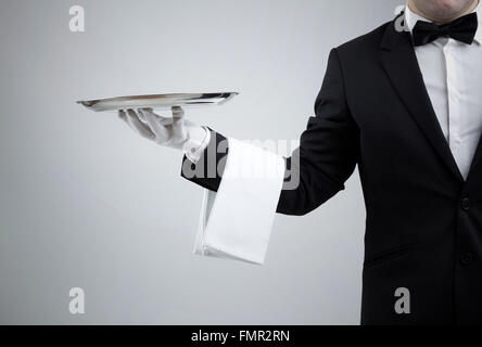 Waiter holding empty silver tray sur fond gris Banque D'Images