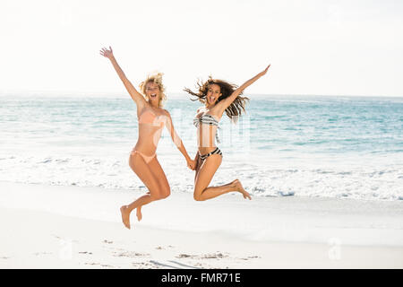 Belle amis excités de sauter sur la plage Banque D'Images