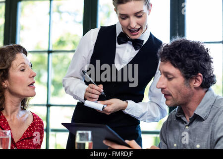 Jeune serveuse prendre une commande à partir d'un couple Banque D'Images