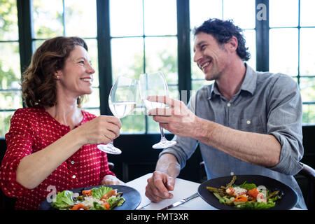 Happy middle-aged couple toasting champagne flutes tout en déjeunant Banque D'Images