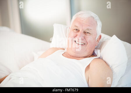 Portrait of senior man relaxing on bed Banque D'Images