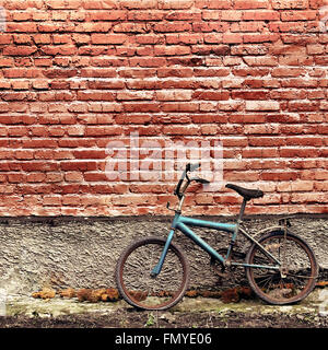 Old rusty vintage bicycle appuyé contre un mur de briques Banque D'Images