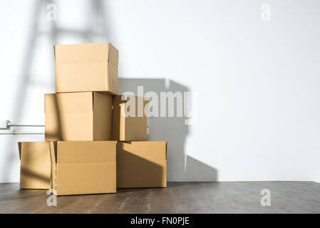 Pile de boîtes de carton sur fond blanc avec l'ombre de l'échelle, personne ne Banque D'Images