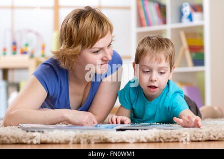 Mère et fils lecture sur un tapis dans la chambre Banque D'Images