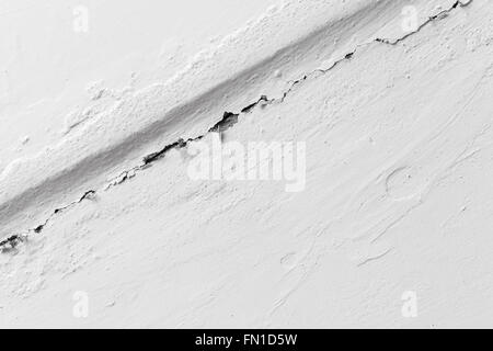 Fissure dans le mur peint en blanc, texture photo gros plan Banque D'Images