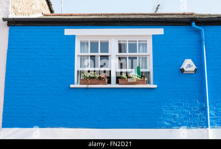 Sur le mur bleu vif et blanc maison mitoyenne d'alarme antivol et fenêtre Banque D'Images