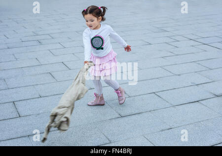 Heureux trois ans, fille jouant avec son manteau dans la ville. Selective focus Banque D'Images