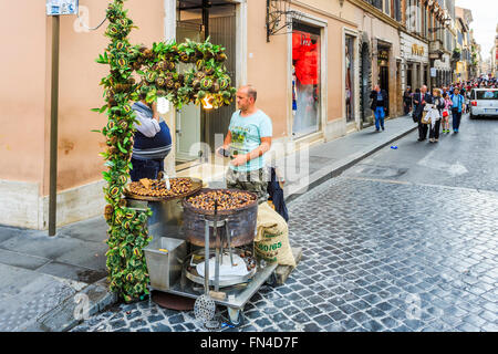 L'homme local, un vendeur de rue la vente de châtaignes grillées sur le bord de la route d'une rue pavée, d'Espagne, Rome, Italie Banque D'Images