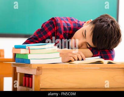 Male Student dort sur le desk in classroom Banque D'Images