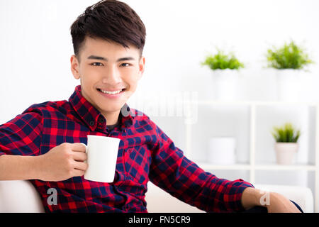 Jeune homme heureux de vous détendre sur le canapé Banque D'Images