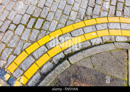 Ligne Jaune double aucun stationnement marquages routiers sur une surface terminée en blocs de granit pavés Banque D'Images