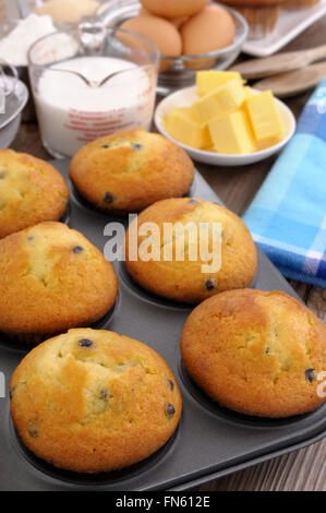 Ingrédients sur une table en bois avec des petits muffins (accent sur les deux muffins au bas de la photo). Banque D'Images