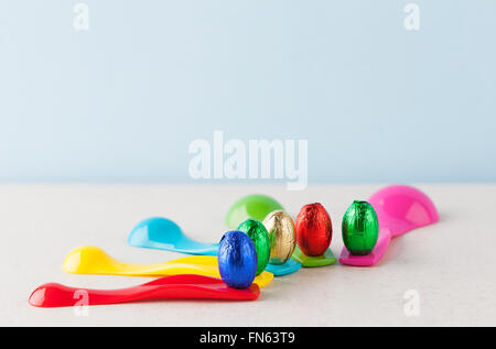 Oeufs de Pâques en chocolat enveloppés de papier aluminium colorés placés sur les tasses à mesurer. Profondeur de champ Banque D'Images