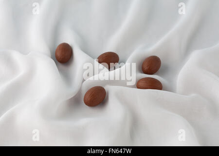 Oeufs de Pâques au chocolat blanc délicat entre les plis de tissu de gaze qui ressemble à du lait. Profondeur de champ. Banque D'Images