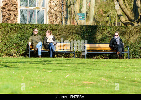 Lund, Suède - 12 mars 2016 : Des inconnus reposant sur banc de parc profitant de l'ensoleillement au début du printemps. L'Open University publiquement Banque D'Images