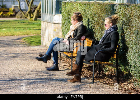 Lund, Suède - 12 mars 2016 : Des inconnus reposant sur banc de parc profitant de l'ensoleillement au début du printemps. L'Open University publiquement Banque D'Images