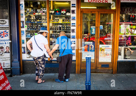 Un couple regardant par la fenêtre de la boutique de téléphonie mobile, Ramsgate, Kent, UK Banque D'Images