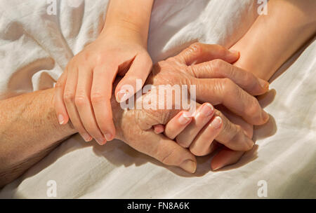 Mains de grand-mère et petit-fils dans le lit Banque D'Images