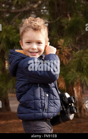 Smiling Boy dans park holding binoculars Banque D'Images