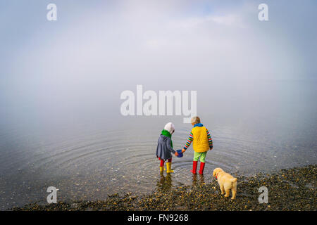 Garçon, fille et chiot golden retriever dog au bord de l'eau Banque D'Images