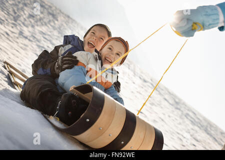 Une personne tirant deux enfants sur une luge. Banque D'Images