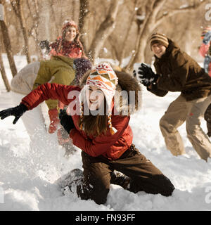 Un groupe de quatre enfants d'avoir une bataille de boules de neige. Banque D'Images