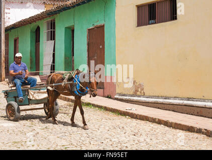 La vie quotidienne à Cuba - homme cheval et panier le long de la rue pavée à Trinidad, Cuba en Mars Banque D'Images