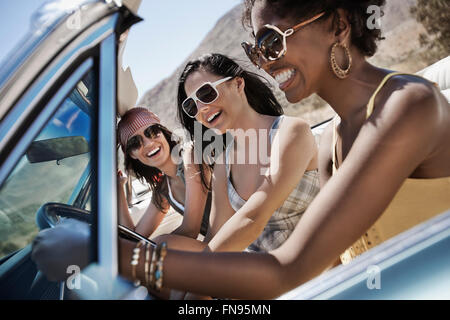 Trois jeunes dans une voiture décapotable bleu pâle, la conduite sur route ouverte sur une plaine sèche, Banque D'Images