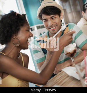 Un jeune homme et femme partagent une coupe de glaces. Banque D'Images