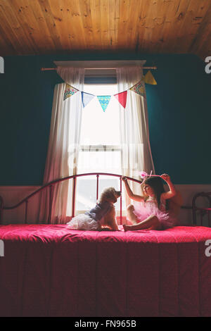 Girl sitting on bed jouer avec chiot golden retriever dog Banque D'Images