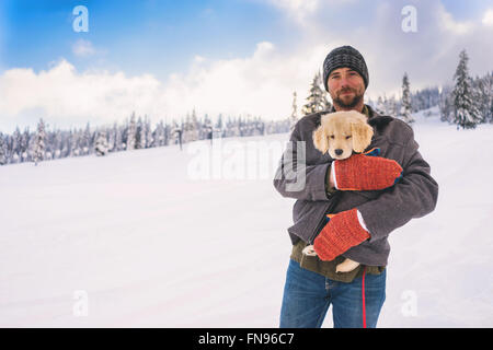 Man holding chiot golden retriever chien dans son manteau Banque D'Images