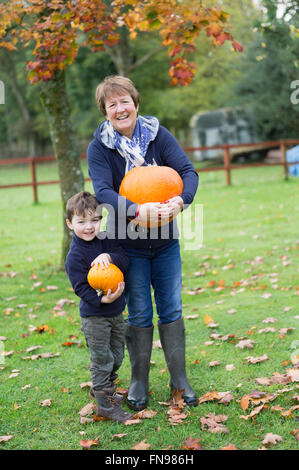 Une femme mature et d'un petit boy holding pumpkins, grandes et petites. Banque D'Images