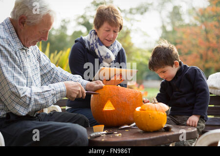 Deux adultes et un petit enfant avec de grandes lanternes citrouille citrouilles, créant pour l'Halloween. Banque D'Images