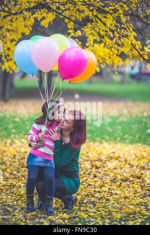 Girl holding balloons embrassant sa mère