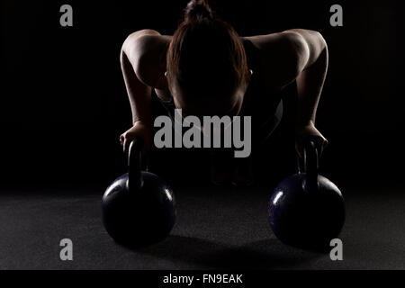 Woman doing press ups sur électrique cloches Banque D'Images