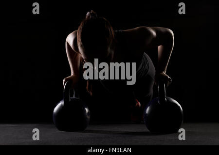 Woman doing press ups sur électrique cloches Banque D'Images