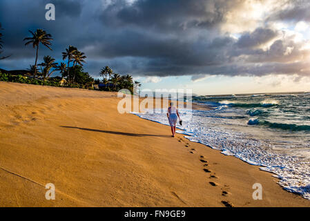 Vue arrière de l'homme marchant sur la plage, North Shore, Hawaii, États-Unis Banque D'Images