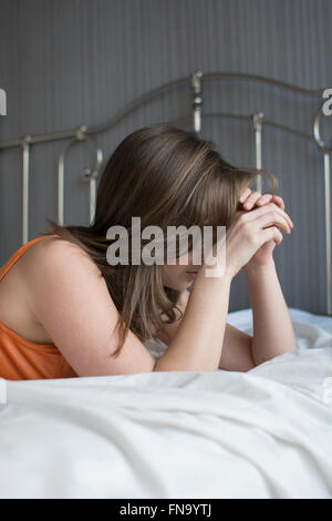 Jeune femme déprimée head in hands in bed Banque D'Images