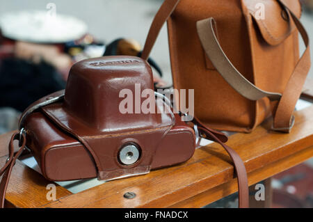 Old vintage 35mm appareil photo reflex en cas de cuir Poche sur du marché de la photographie arrête sur carboot sale in Bath, Royaume-Uni. Banque D'Images