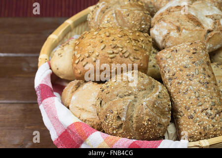 Différents types de farine de pâtisserie sont dans un panier en osier, qui est allongé sur une table en bois. Banque D'Images